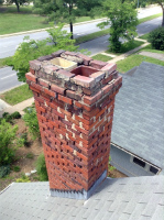 Red brick chimney with extensive damage, cracks, and gaps in masonry