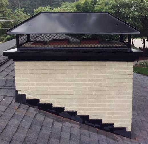 White brick chimney after repairs with new black flashing and new black metal chase cover and chimney cap