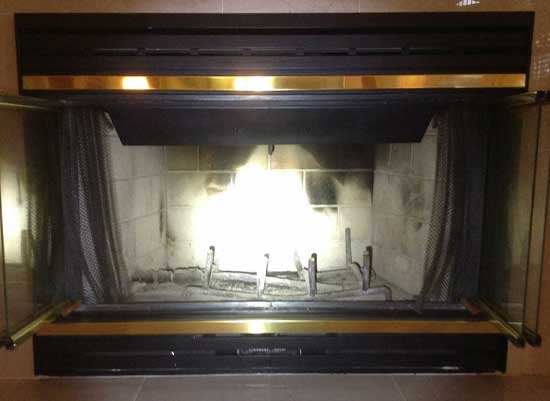 Fireplace with black and gold frame with damaged masonry before firebox repair