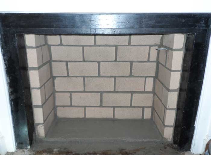 Fireplace with black metal surround and new masonry after firebox repair