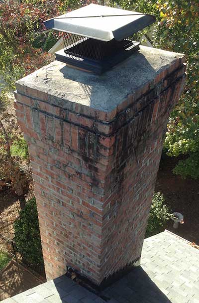 Damaged Brick Chimney Crown Before Repair - trees in the background