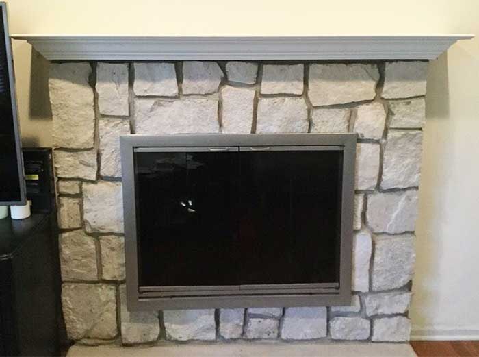 stone fireplace with stainless steel frame insert and white wooden mantel