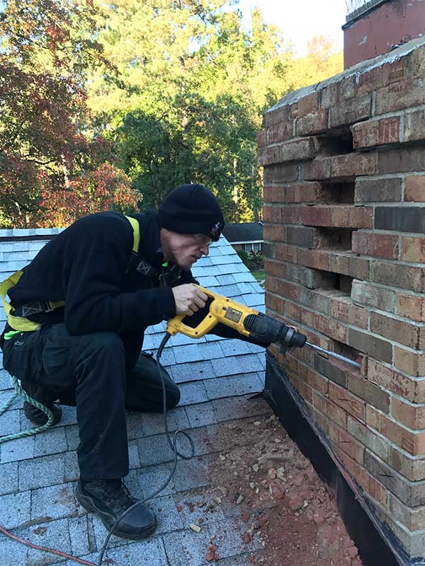 chimney technician repairing masonry chimney by removing bricks