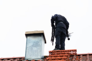 Chimney sweep standing on roof of home working