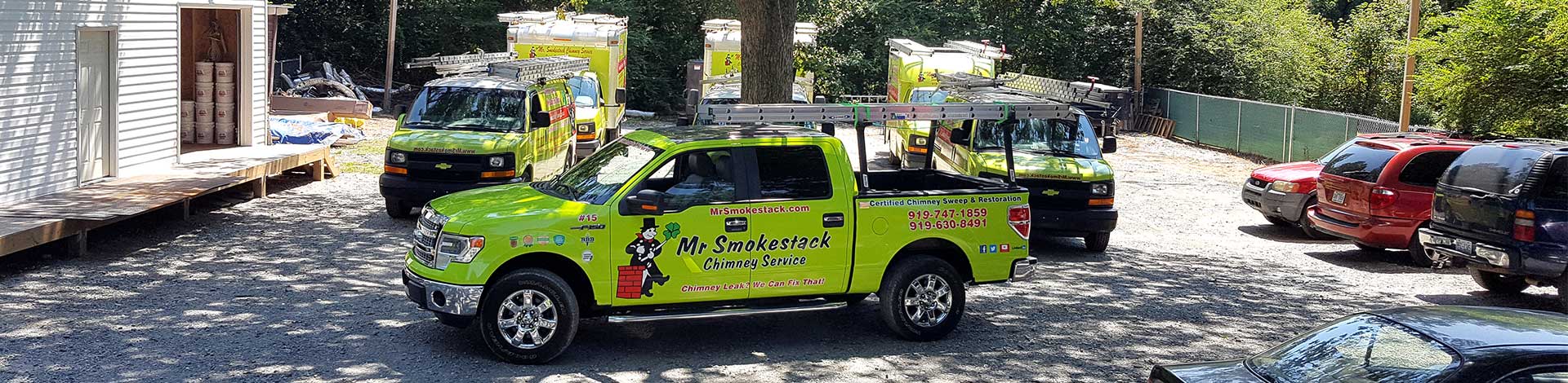 Neon Green Mr. Smokestack service trucks and vans parked in front of the shop