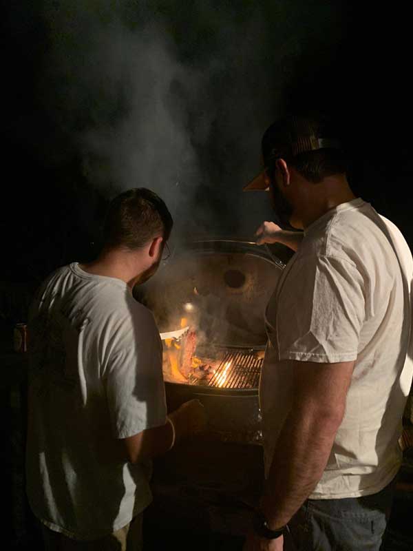 Stock Image of Men Grilling at Night guys enjoying outdoor grilling at night