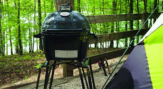 primo outdoor grill set up next to a tent in a wooded campsite
