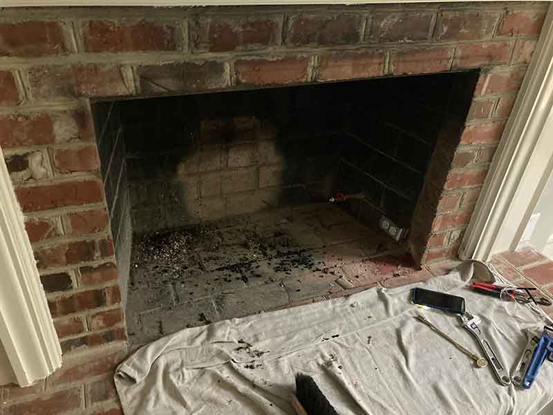 Brick Fireplace with white mantle with black soot in firebox before fireplace restoration