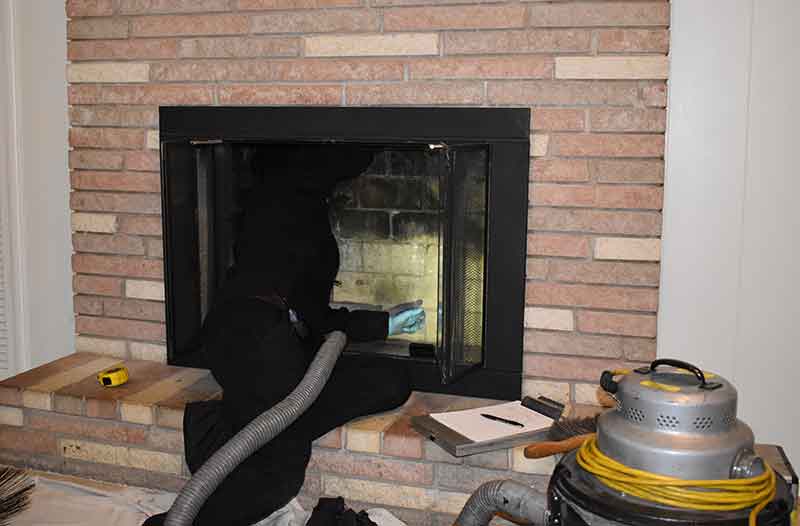 chimney sweep technician vacuuming fireplace firebox