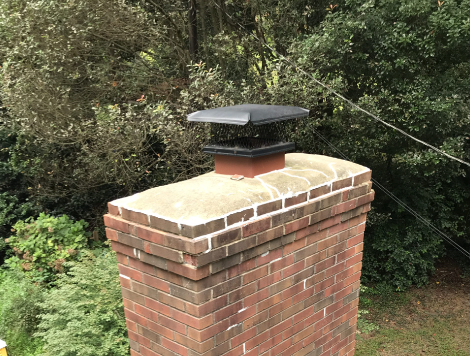 Brick Chimney with small black chimney cap and exposed chimney crown before more effective cap and chase cover was installed