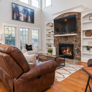 living room with a brown couch in front of a lit fireplace