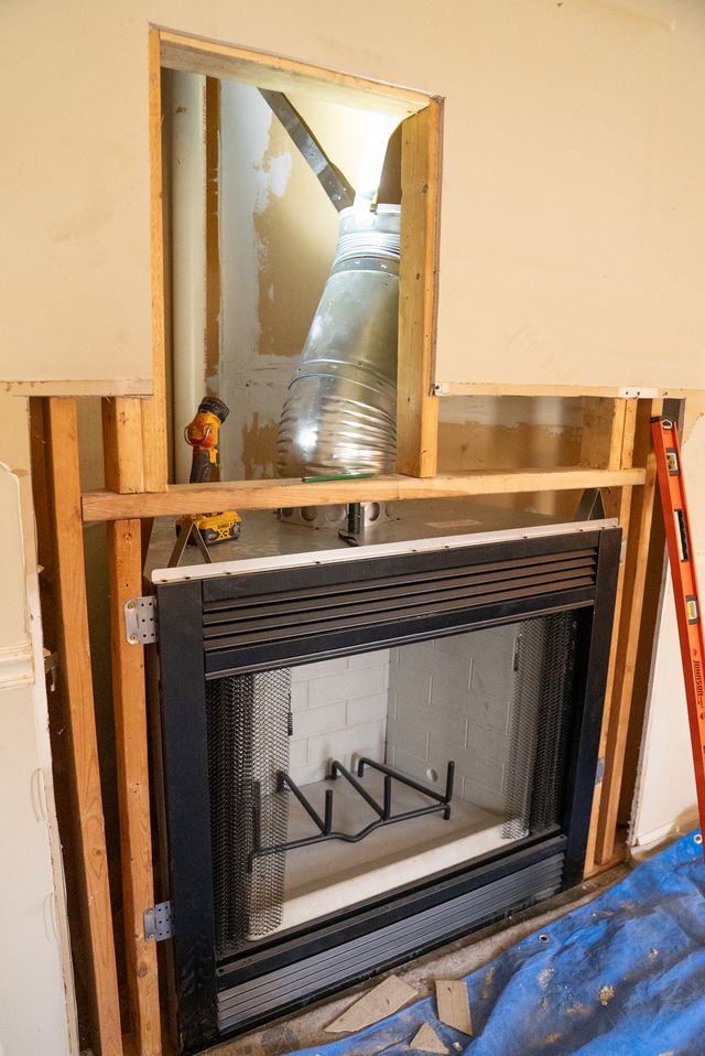 stone fireplace with stainless steel frame insert and white wooden mantel